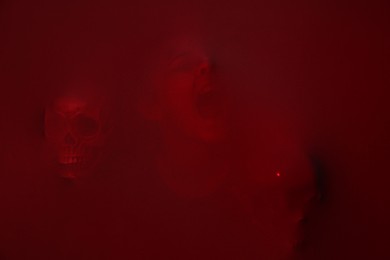 Photo of Silhouette of creepy ghost with skulls behind red cloth