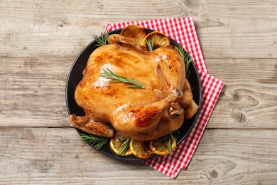 Photo of Tasty roasted chicken with rosemary and lemon on wooden table, top view