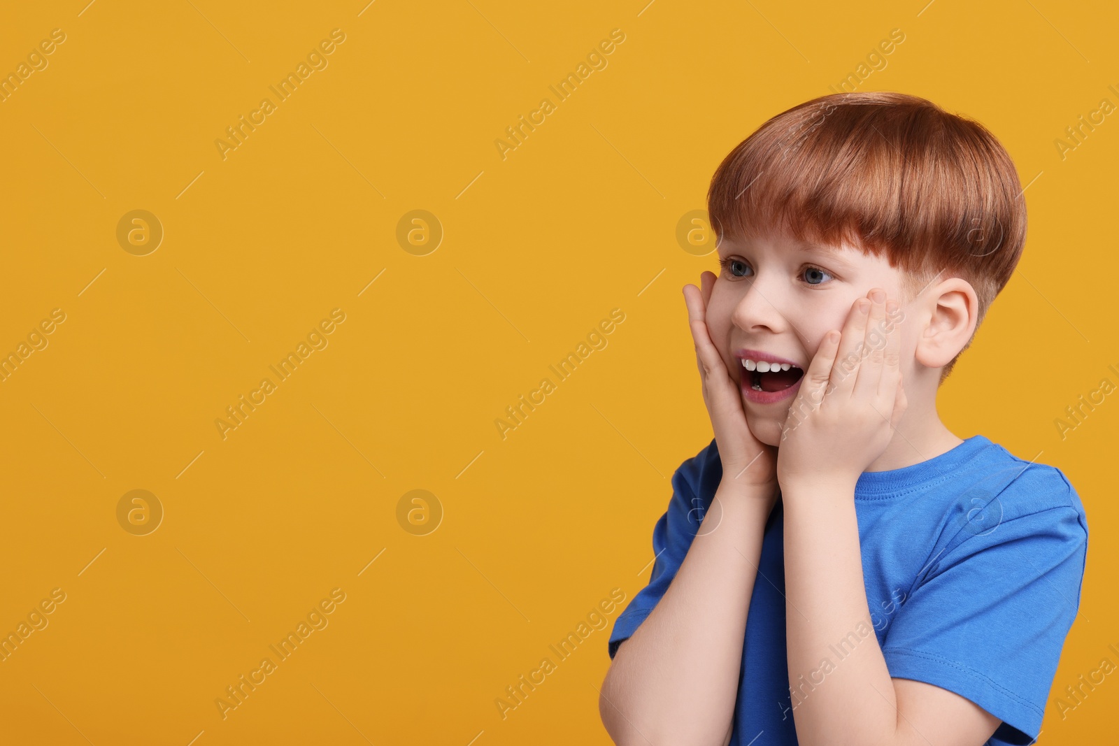 Photo of Portrait of surprised little boy on orange background, space for text