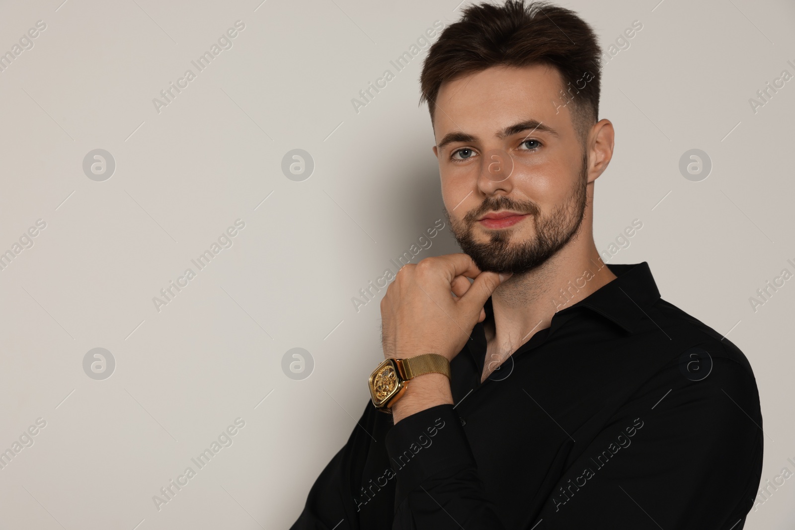 Photo of Handsome man in black shirt on light grey background, space for text