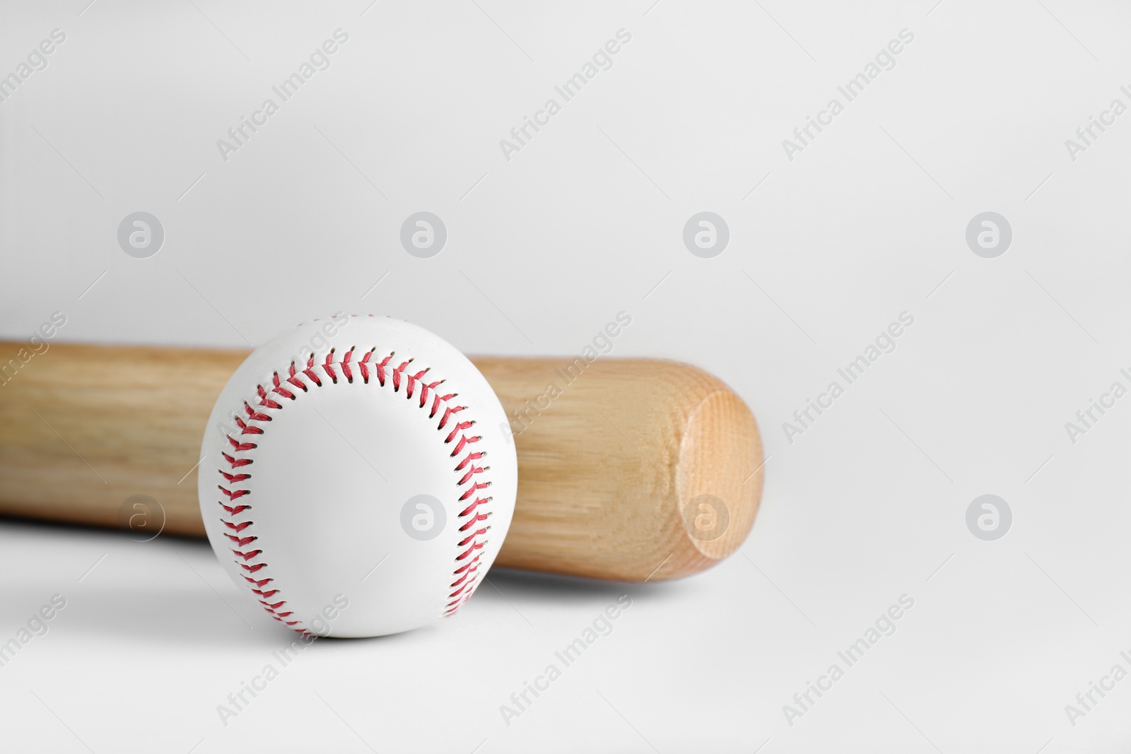 Photo of Wooden baseball bat and ball on white background. Sports equipment