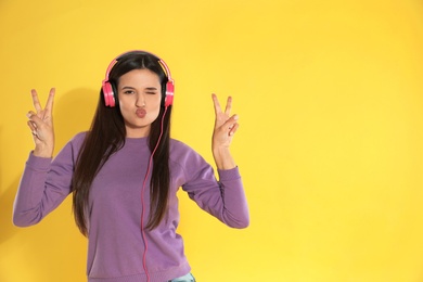 Photo of Attractive young woman enjoying music in headphones on color background. Space for text