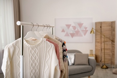 Photo of Wardrobe rack with stylish warm clothes indoors. Space for text