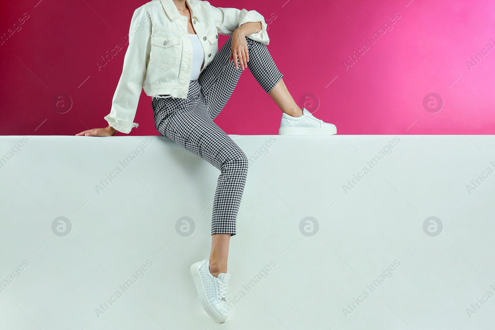 Photo of Woman in stylish shoes sitting on color background, closeup