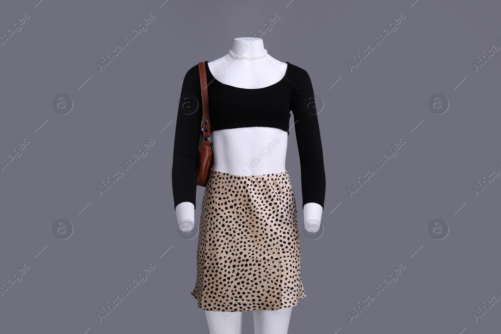 Photo of Female mannequin with necklace and bag dressed in stylish outfit on grey background