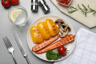 Photo of Delicious grilled vegetables served on grey table, flat lay