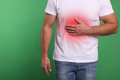 Image of Man suffering from stomach pain on green background, closeup