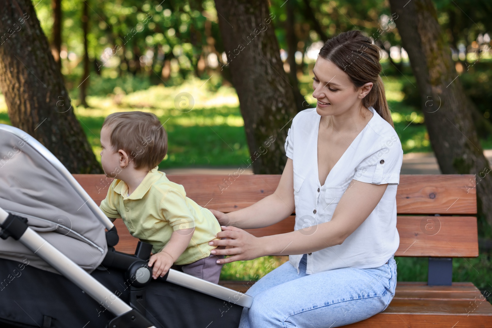 Photo of Happy nanny with cute little boy in stroller in park