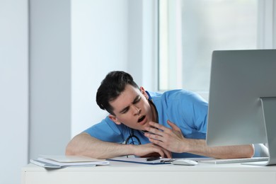 Photo of Exhausted doctor yawning at workplace in hospital