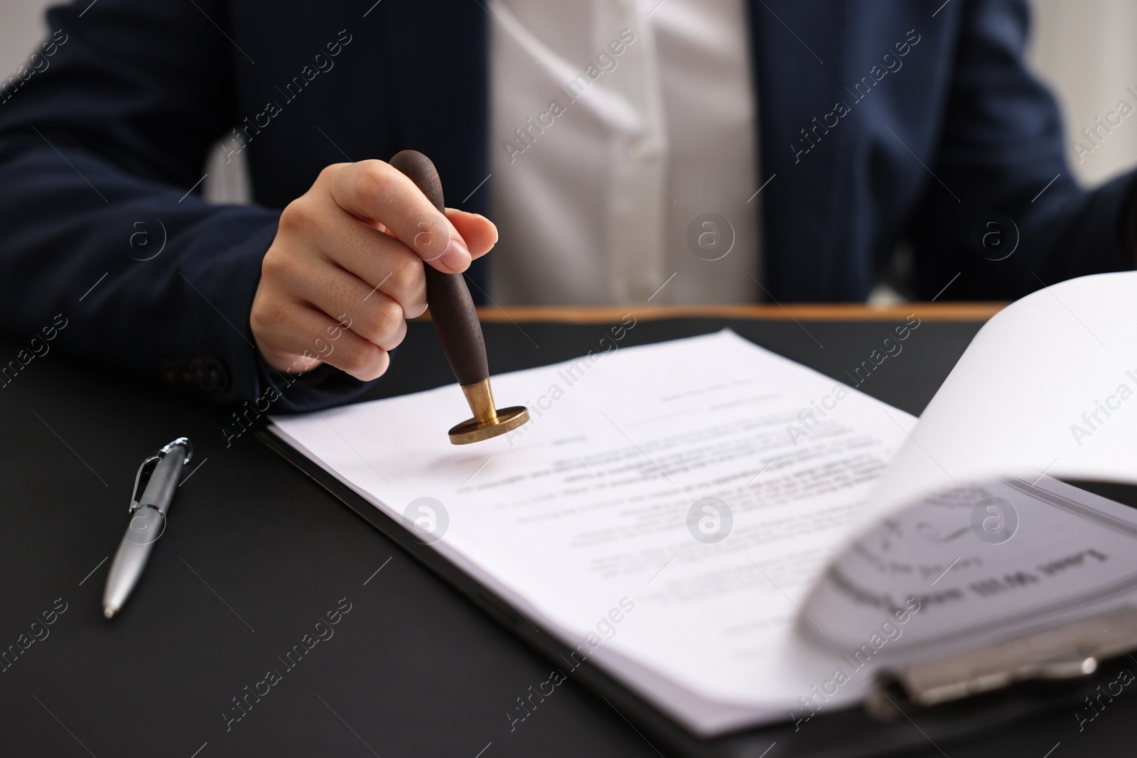 Photo of Notary sealing document at table in office, closeup