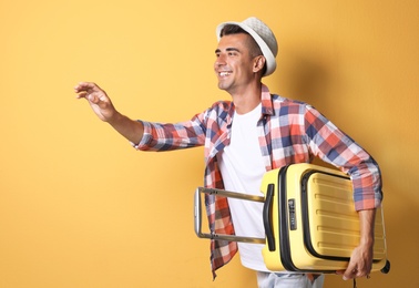 Photo of Young man with suitcase on color background