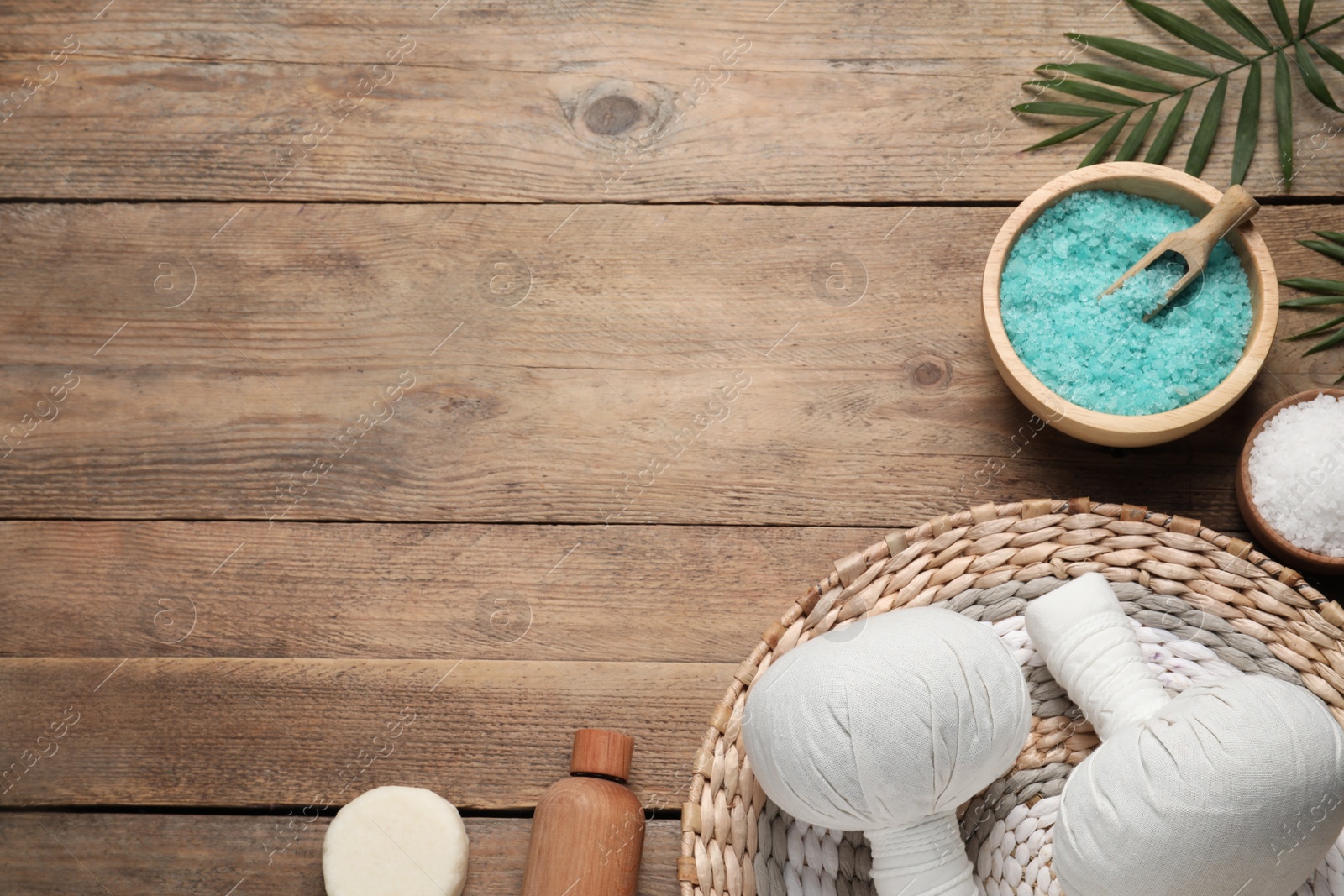 Photo of Flat lay composition with herbal massage bags and other spa products on wooden table. Space for text