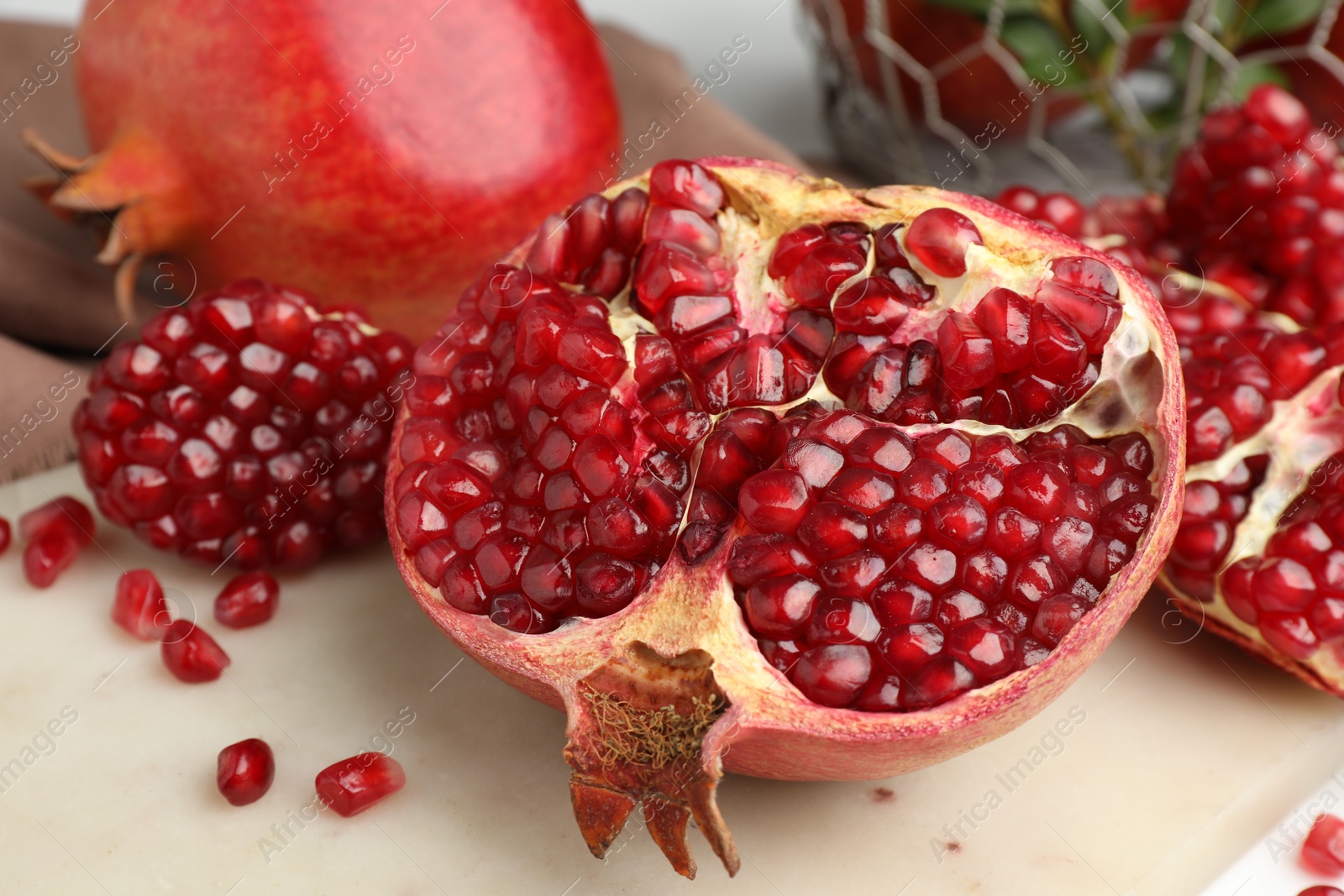 Photo of Piece of fresh pomegranate and seeds on white table, closeup