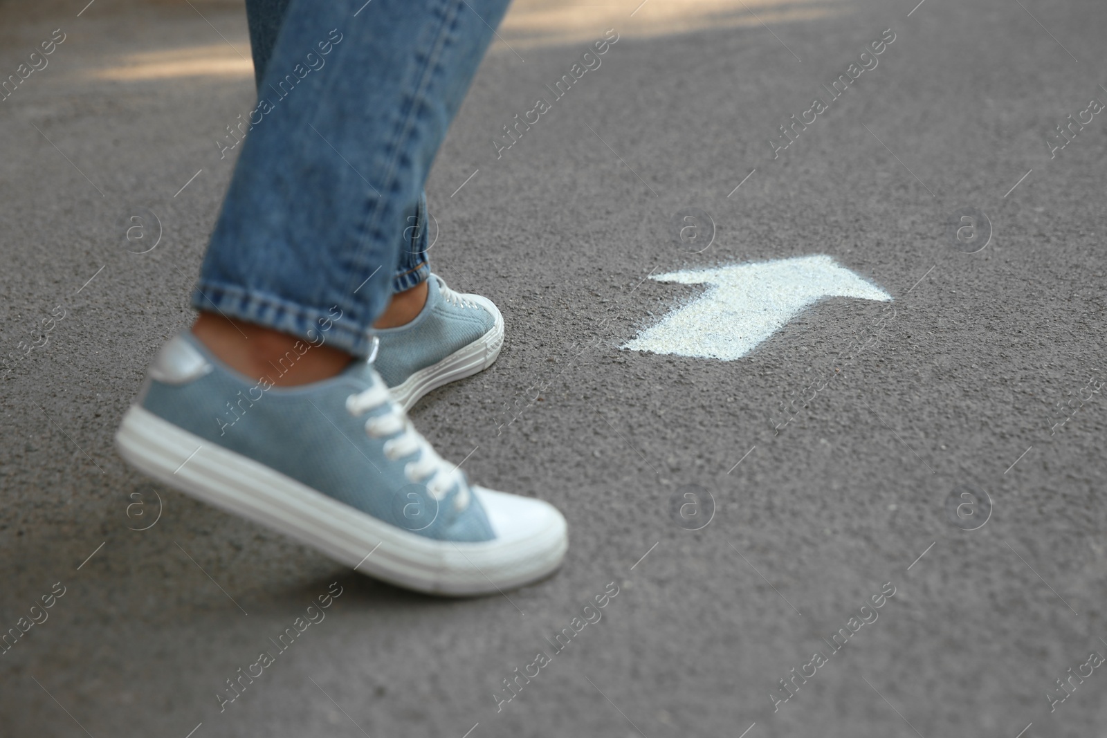 Photo of Person standing near arrow on asphalt, closeup