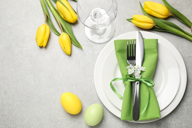 Festive Easter table setting with floral decor on grey background, flat lay