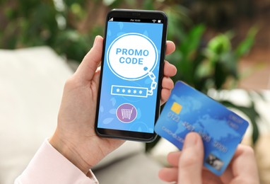 Woman holding credit card and smartphone with activated promo code in online shopping app indoors, closeup