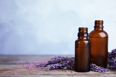 Photo of Bottles with aromatic lavender oil on wooden table. Space for text