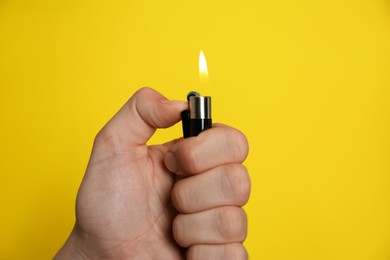 Photo of Man holding lighter on yellow background, closeup