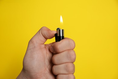 Man holding lighter on yellow background, closeup