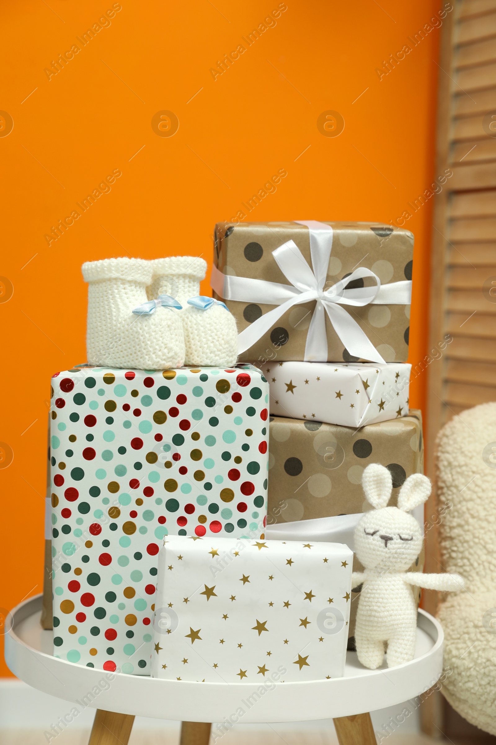 Photo of Baby shower party. Festive decor, booties, toy and gift boxes on white table