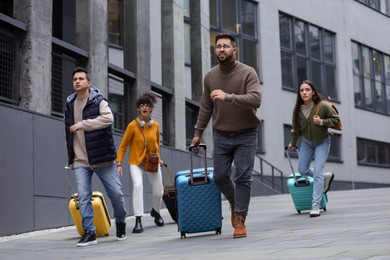 Photo of Being late. Group of people with suitcases running outdoors
