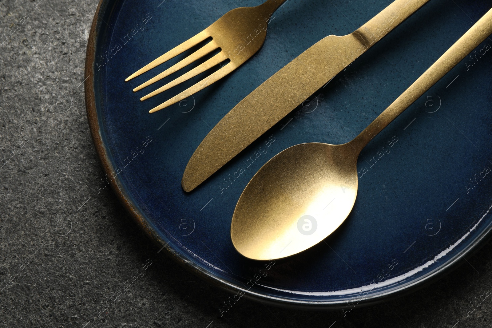 Photo of Stylish golden cutlery and plate on grey table, top view