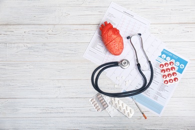 Flat lay composition with stethoscope and pills on wooden background. Cardiology service