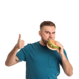 Young man eating tasty burger on white background