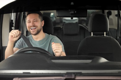 Photo of Listening to radio. Handsome man enjoying music in car, view through windshield