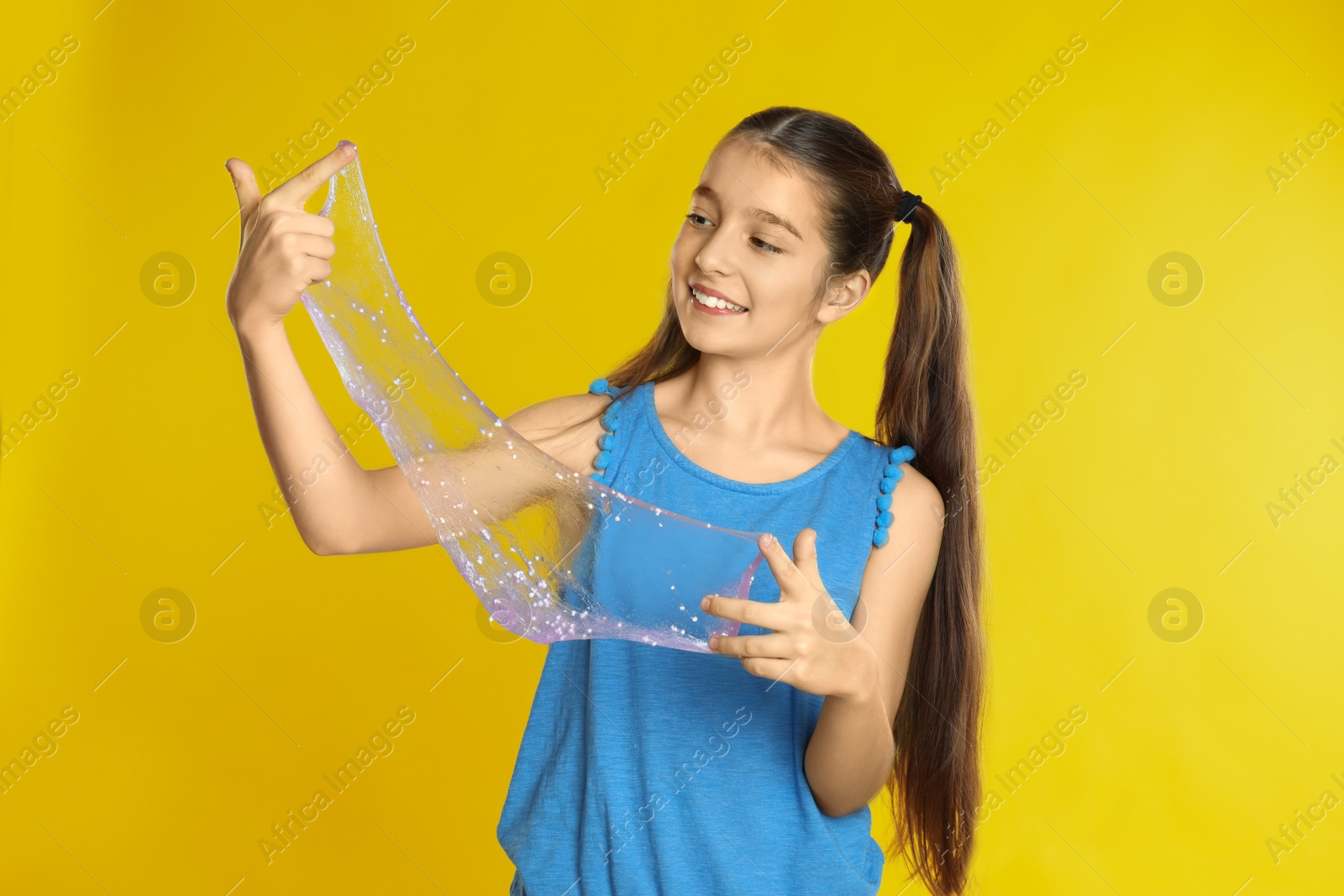 Photo of Preteen girl with slime on yellow background