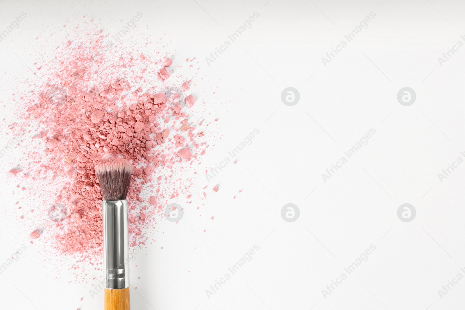 Photo of Makeup brush and scattered blush on white background, top view. Space for text