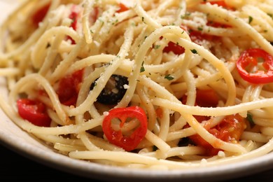 Delicious pasta with olives, tomatoes and parmesan cheese on table, closeup