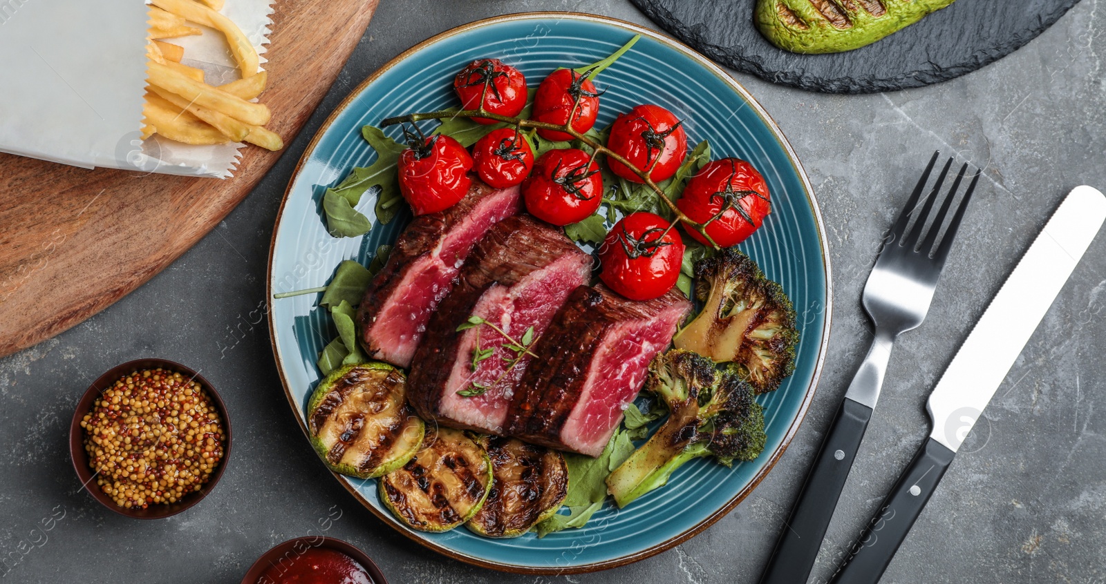 Image of Delicious sliced beef steak served on grey table, flat lay. Banner design