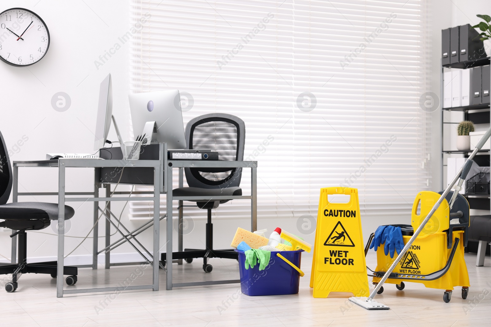 Photo of Cleaning service. Mop, wet floor sign and bucket with supplies in office