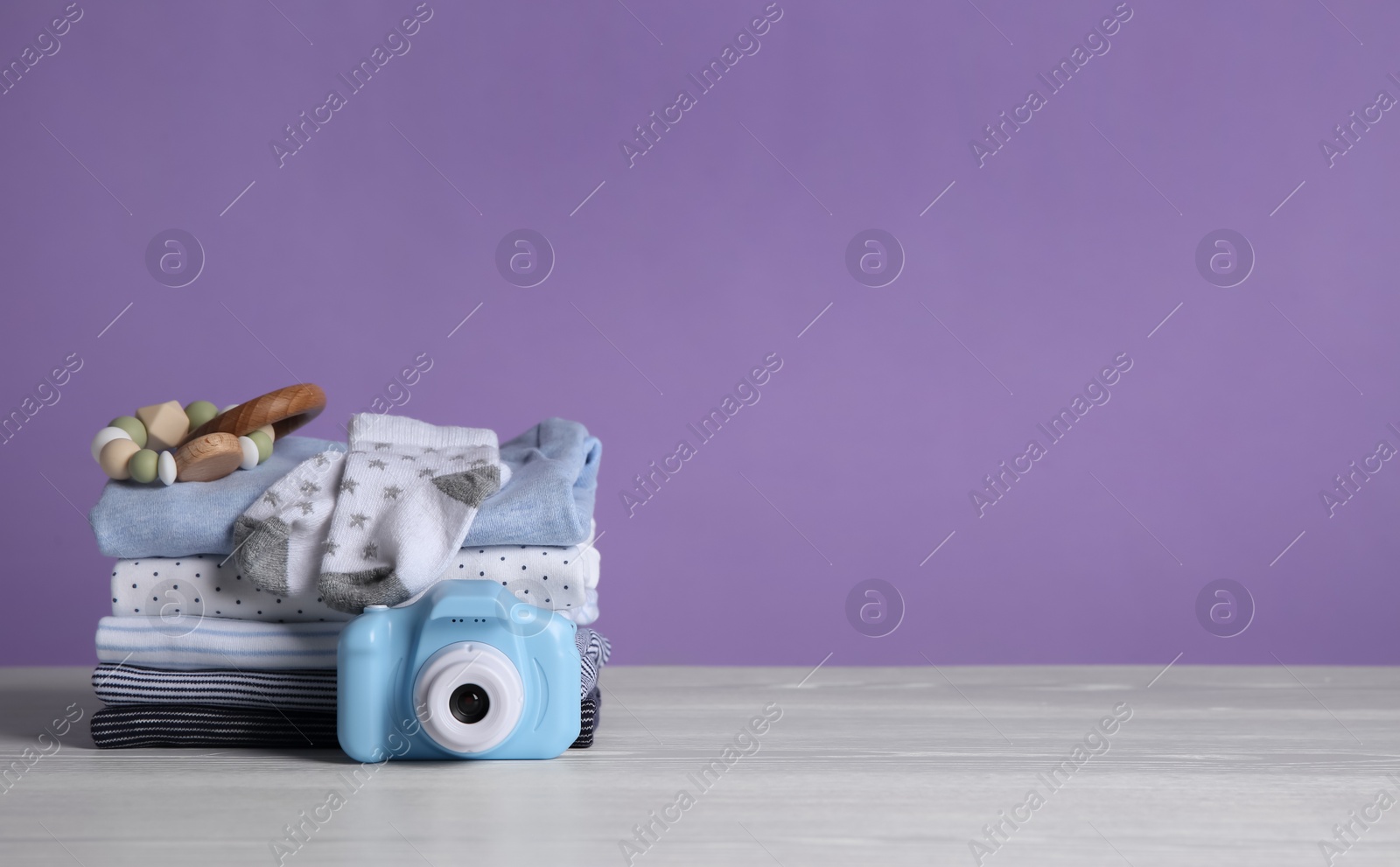 Photo of Children's clothes and toys on white wooden table. Space for text