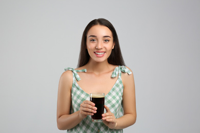 Photo of Beautiful woman with cold kvass on light grey background. Traditional Russian summer drink