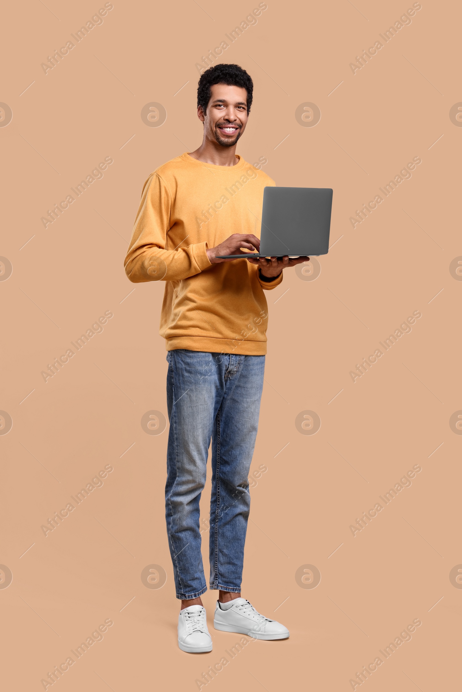 Photo of Happy man with laptop on beige background