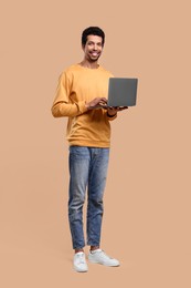 Happy man with laptop on beige background