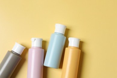 Photo of Cosmetic travel kit. Small containers of personal care products on yellow background, flat lay