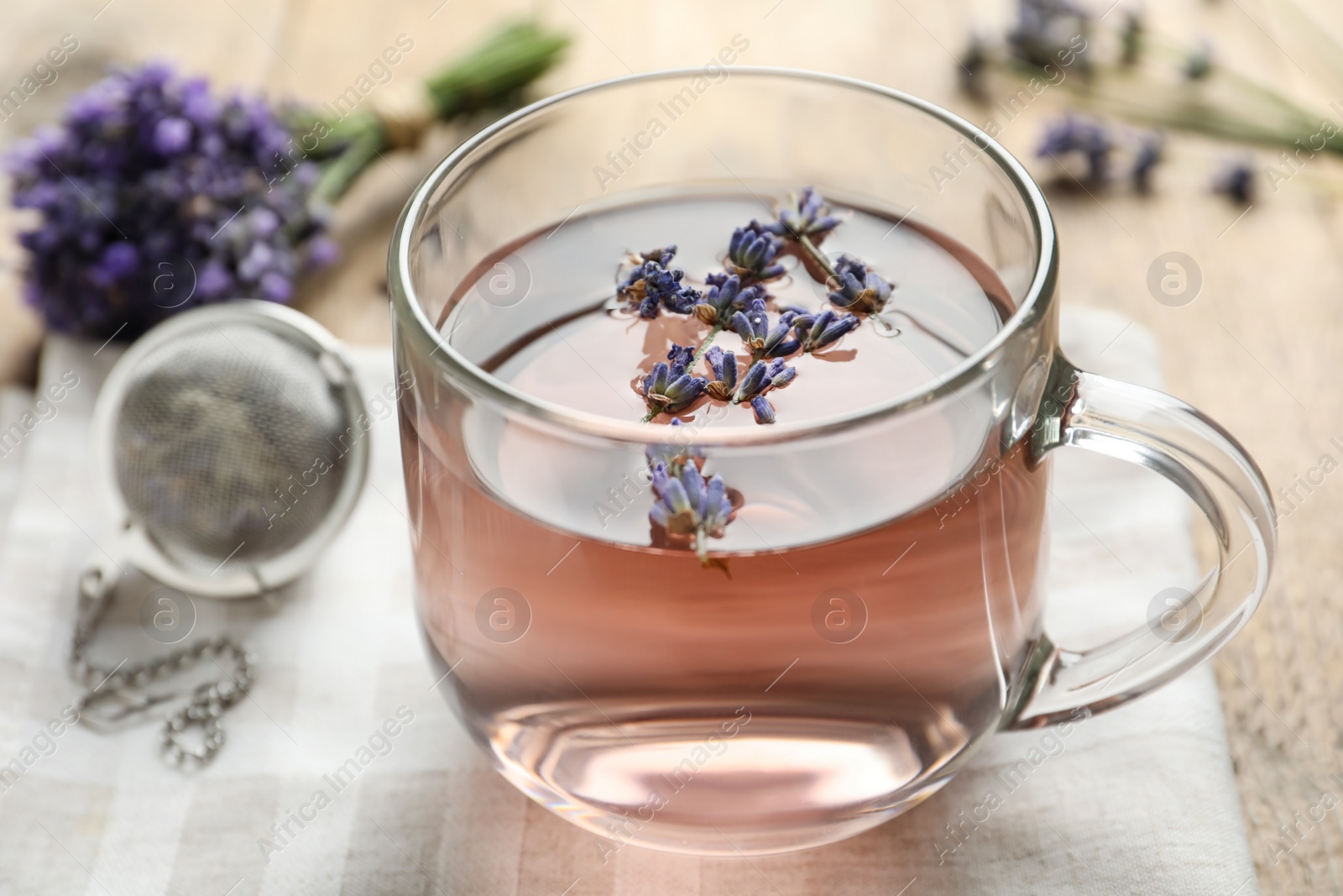 Photo of Fresh delicious tea with lavender in glass cup on wooden table