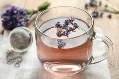 Photo of Fresh delicious tea with lavender in glass cup on wooden table