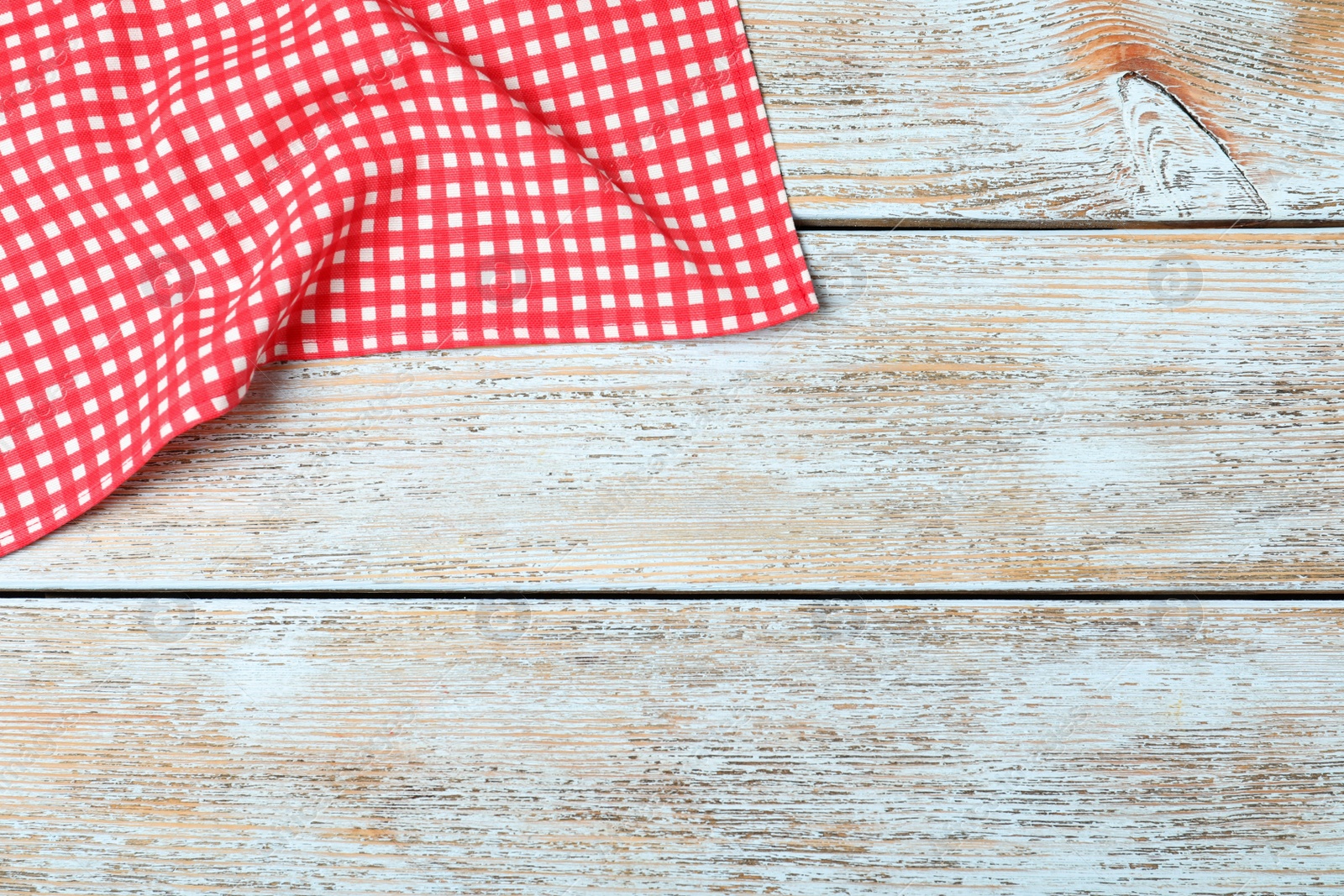 Photo of Checkered picnic blanket on wooden background, top view. Space for text