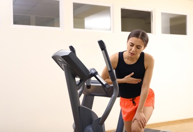 Young woman having heart attack on treadmill in gym