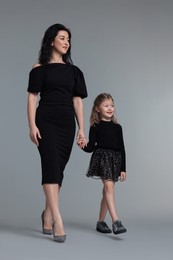 Photo of Beautiful mother with little daughter on grey background