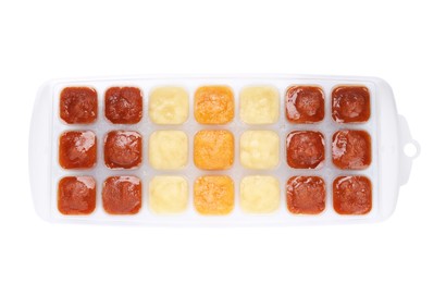 Photo of Different puree in ice cube tray on white background, top view. Ready for freezing