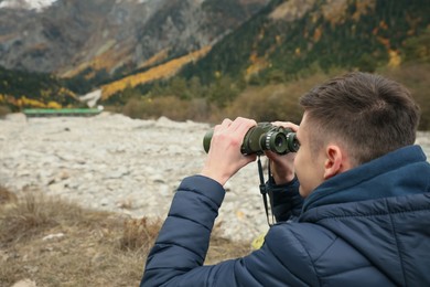 Photo of Boy looking through binoculars in beautiful mountains