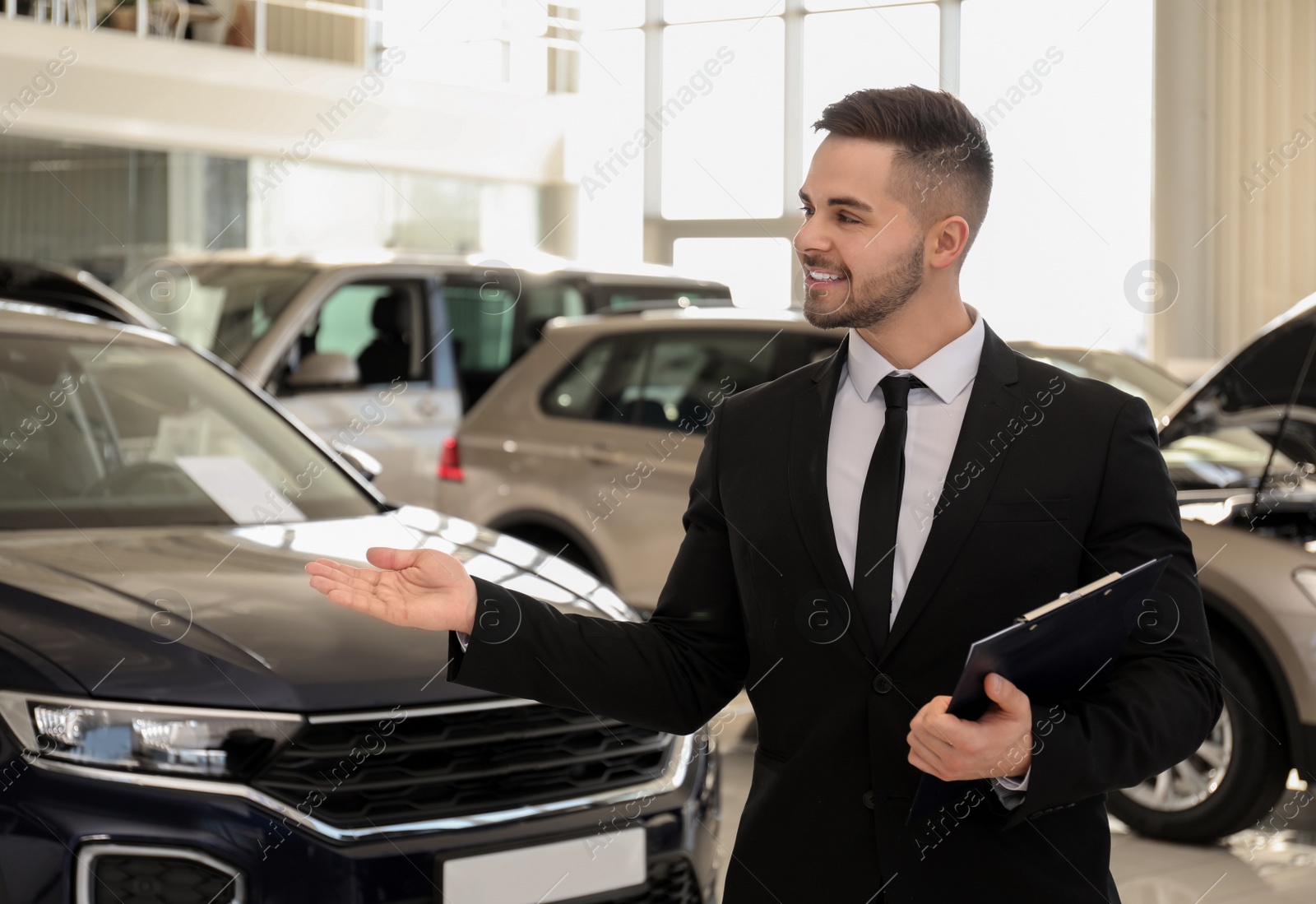 Photo of Young salesman with clipboard in modern car salon