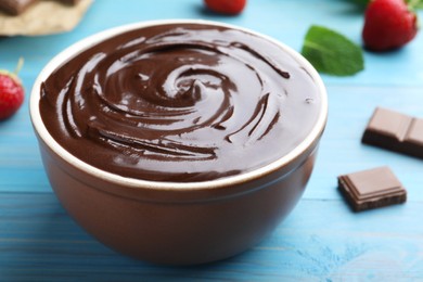 Delicious chocolate cream on light blue wooden table, closeup