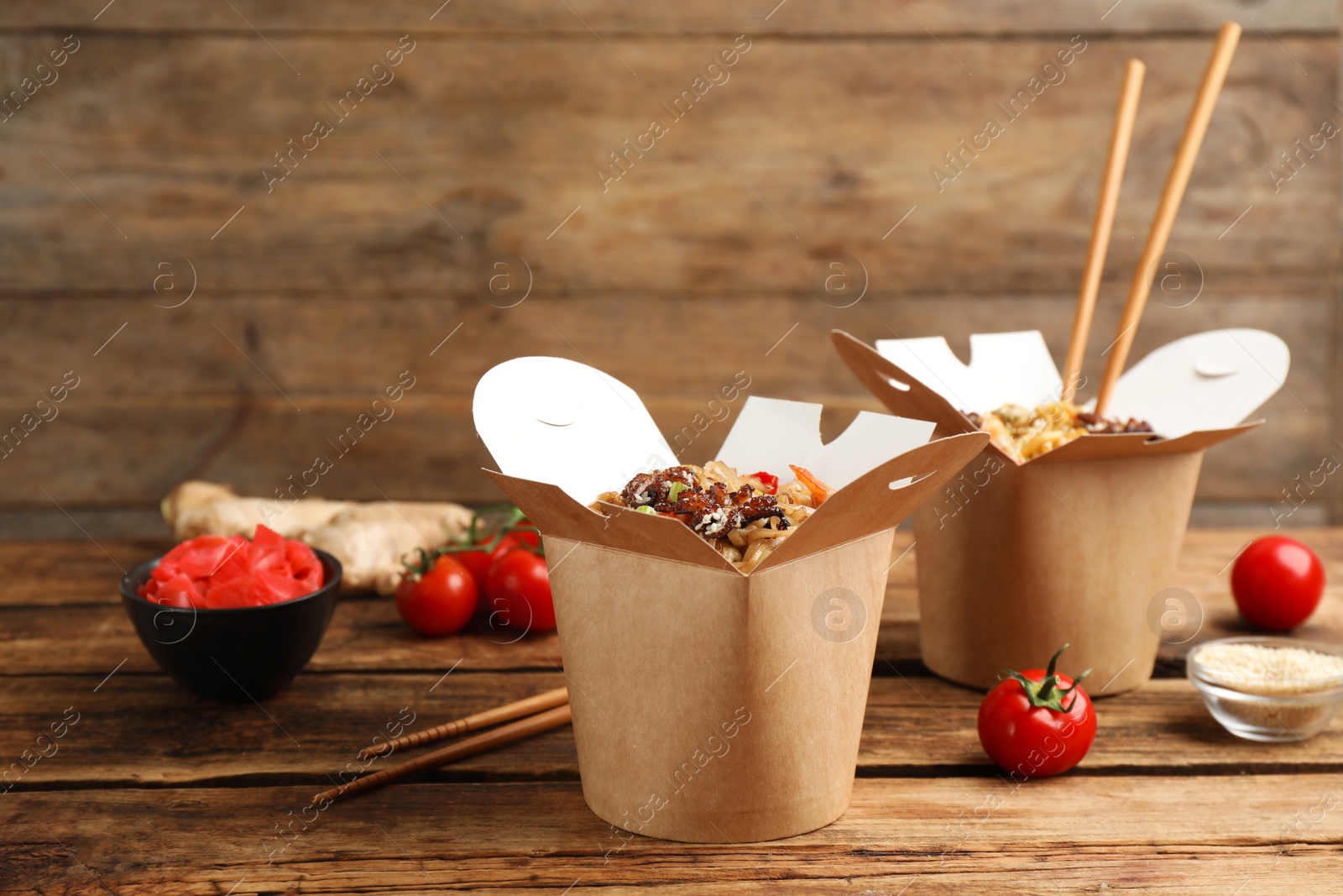 Photo of Boxes of wok noodles with seafood and chopsticks on wooden table