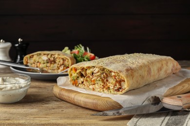 Photo of Tasty strudel with chicken, vegetables and sauce on wooden table